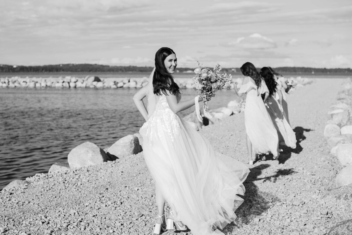 Bride walking along edge of ocean with bridesmaids at Oak Island Resort Wedding, Nova Scotia