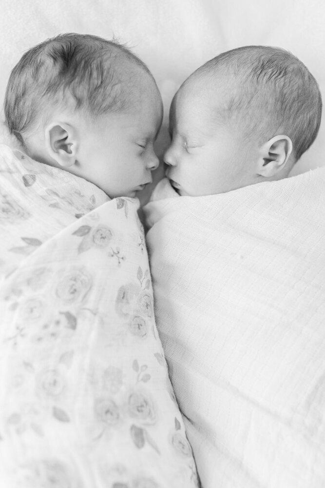 newborn twins sleeping together while swaddled