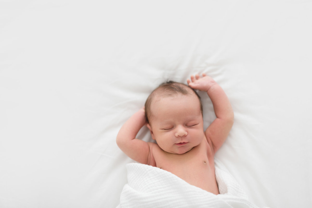 A brand new baby asleep on a white bed