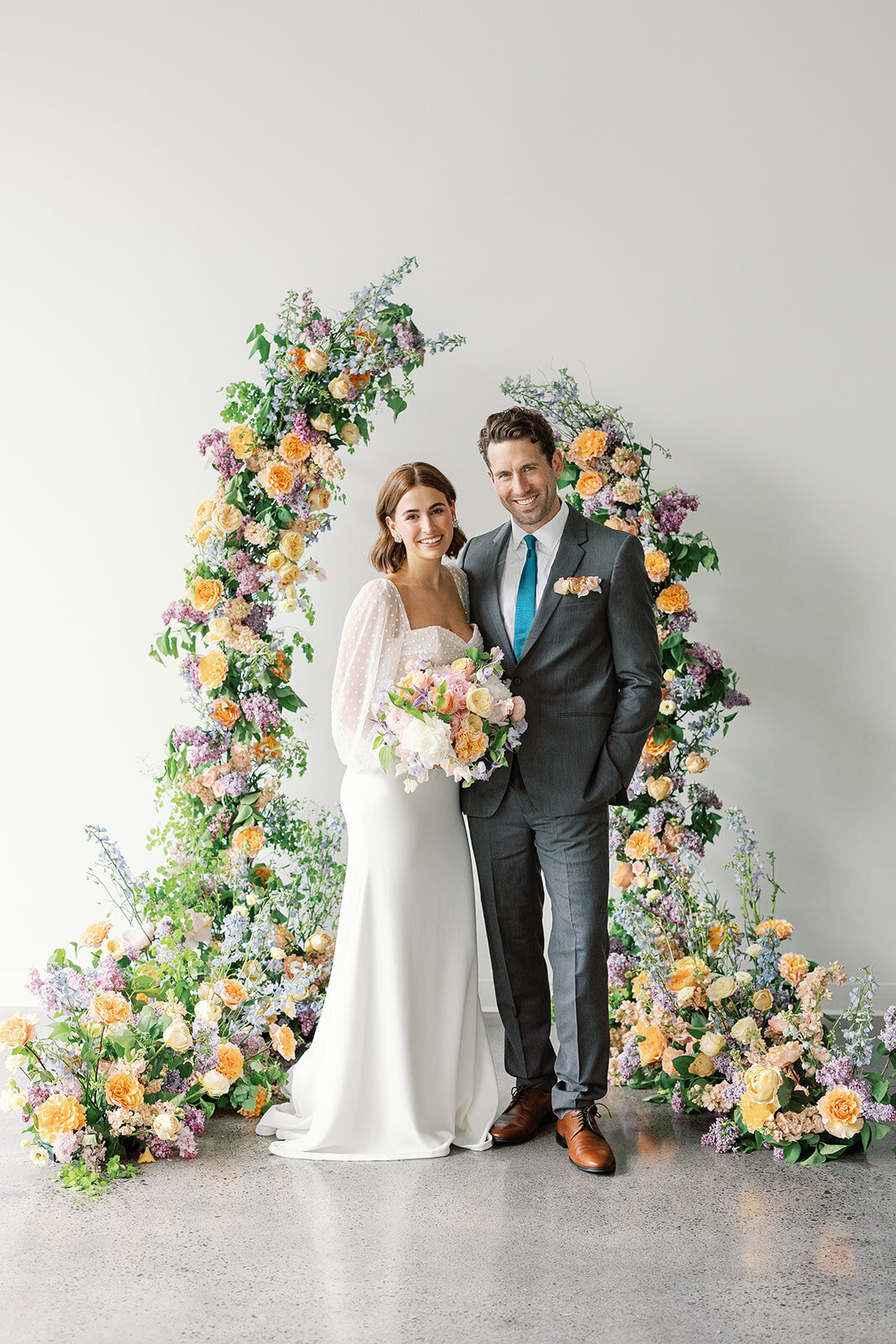 Bride and Groom standing in front of floral arch at Urban Daisy