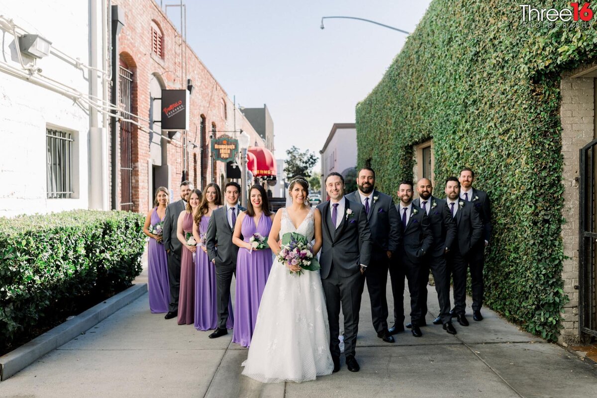 Bride and Groom pose in a V-shape with bridal party in a back alley behind the Villa del Sol wedding venue in downtown Fullerton