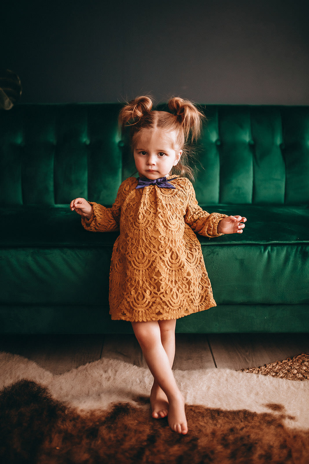 little girl standing next to green couch