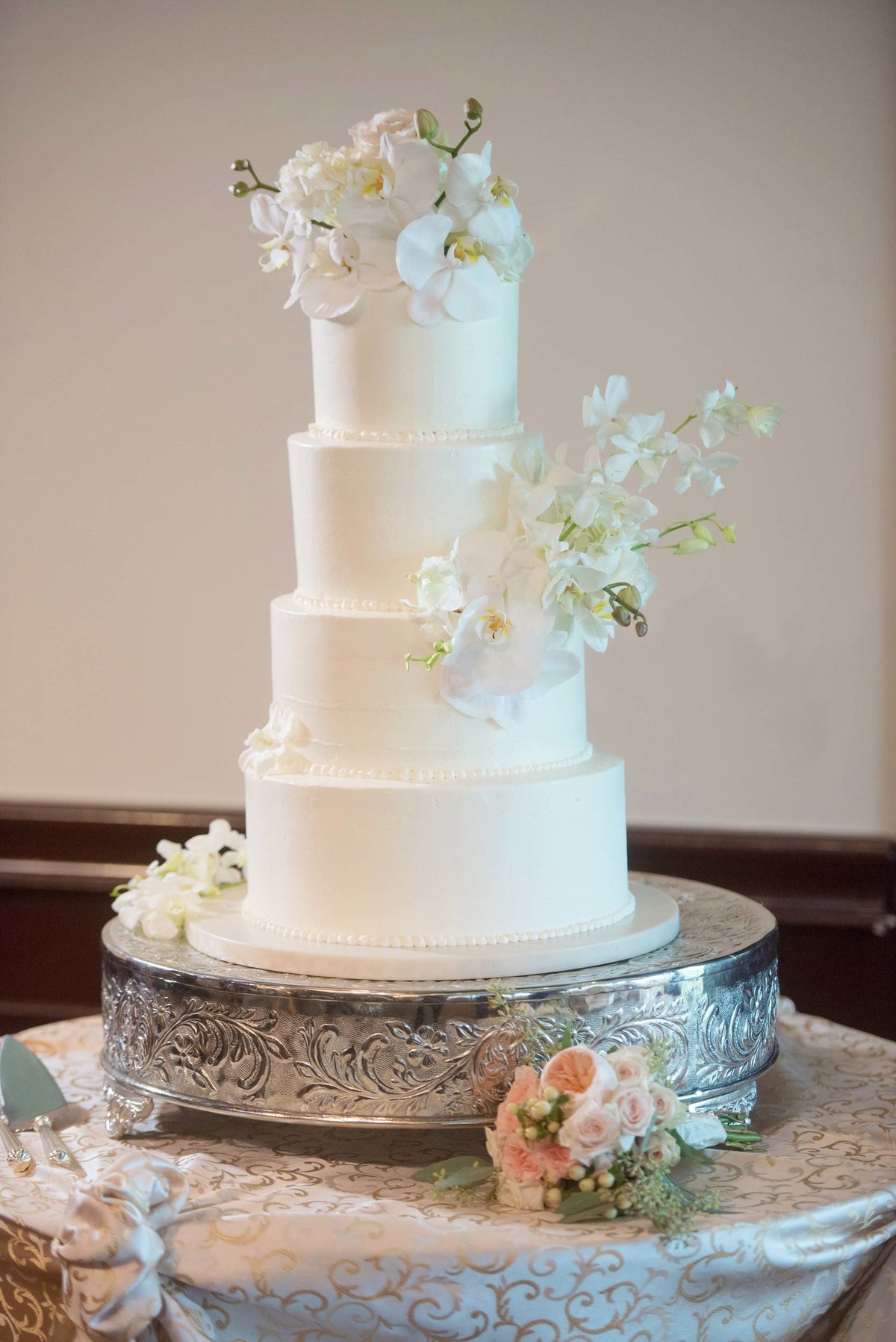 White wedding cake with white flowers at Huntington Crescent Club