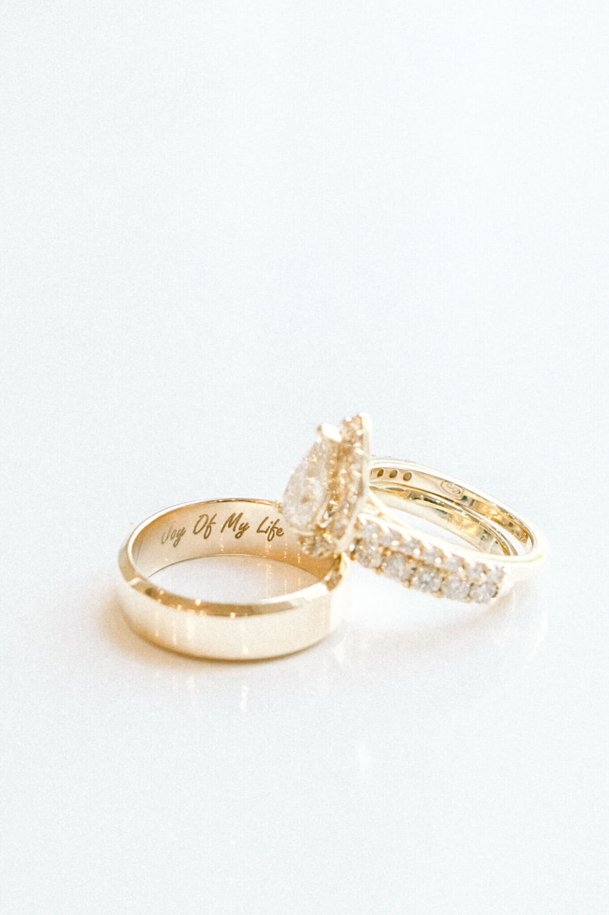 bride and groom wedding rings on white background with the inscription joy of my life inside one ring