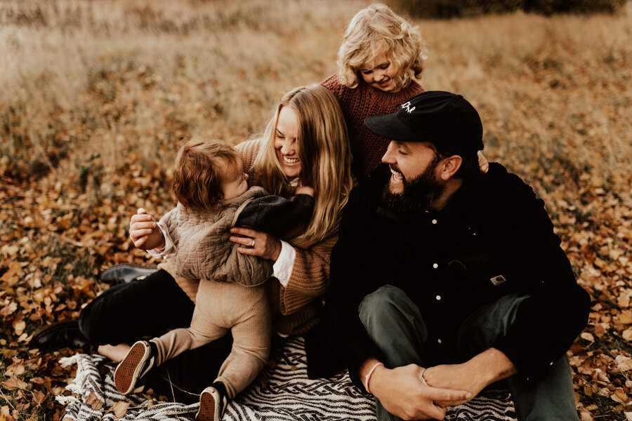 familj busar och skrattar på en filt under familjefotografering med linnsej photography