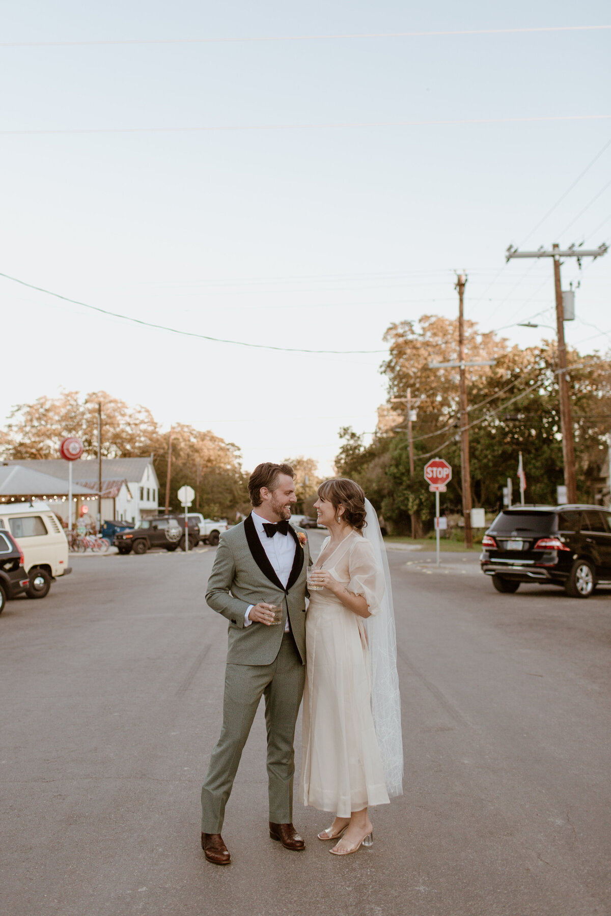 A happy just-married couple hit the streets of Comfort Texas at sunset. Captured by Fort Worth Wedding Photographer, Megan Christine Studio