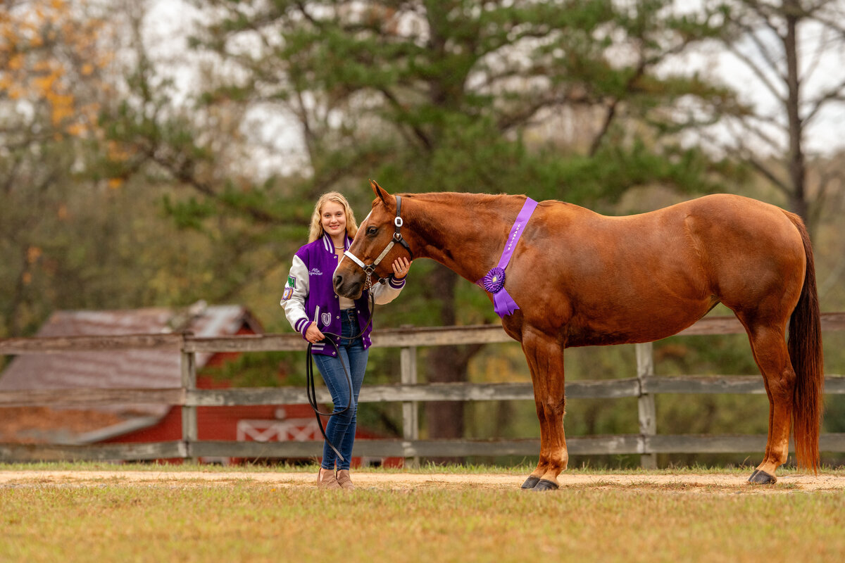 Senior takes photos with her letterman jacket and horse wearing 4H ribbons in Alabama. Senior photo ideas with horses.