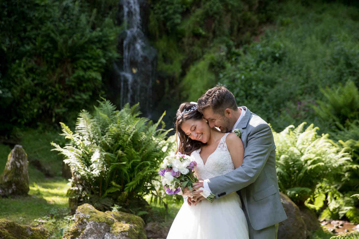 Bride and Groom cuddling by the cascade at Hestercombe Gardens