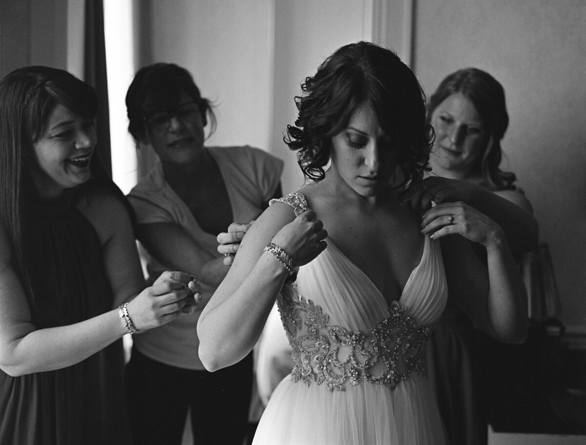 A group of people adjusting a bride's dress.