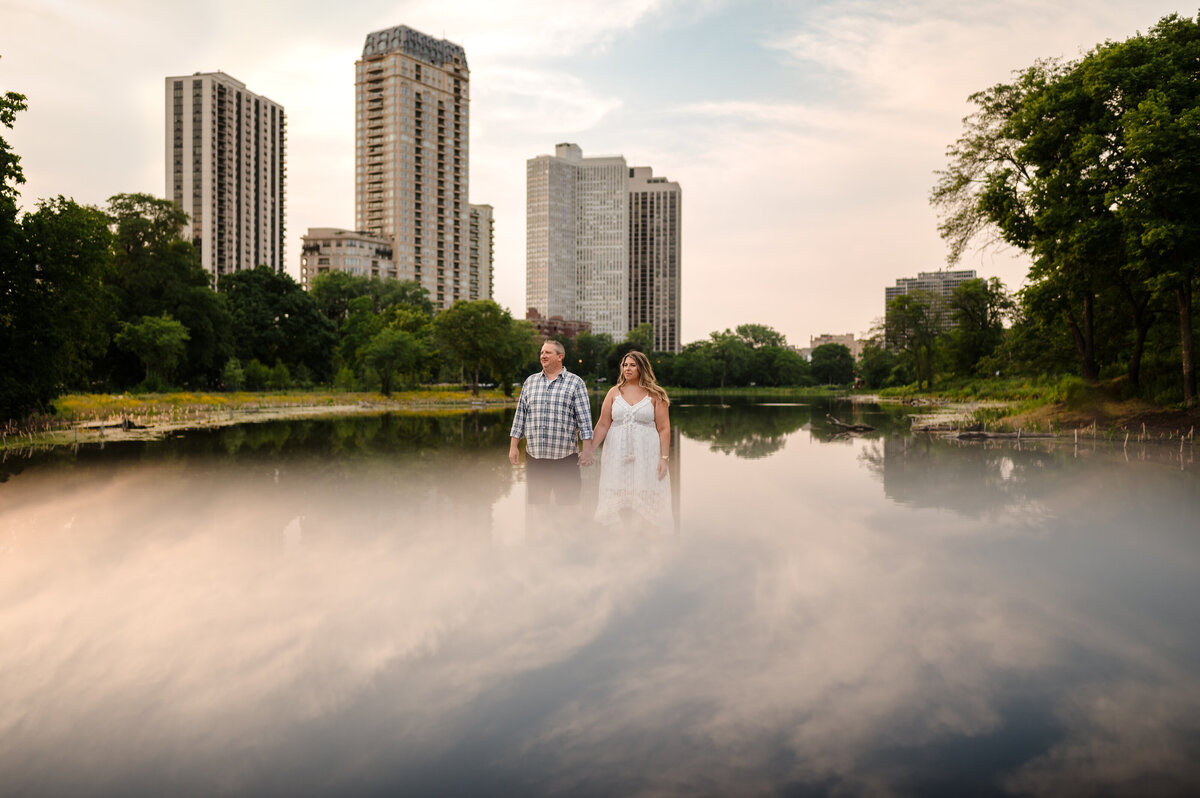 Clouds reflect on pond with couple in Lincoln Park