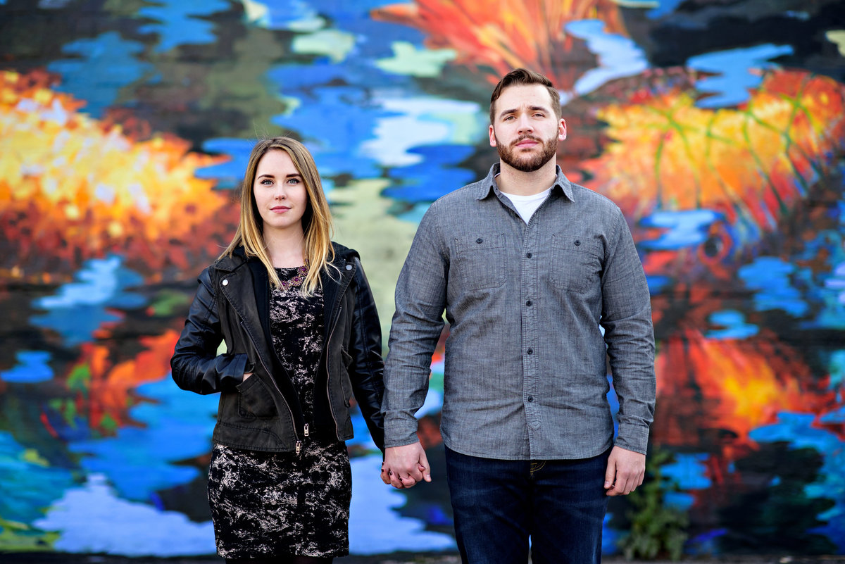 Engaged couple hold hands  in front of a graffiti wall in northern liberties.