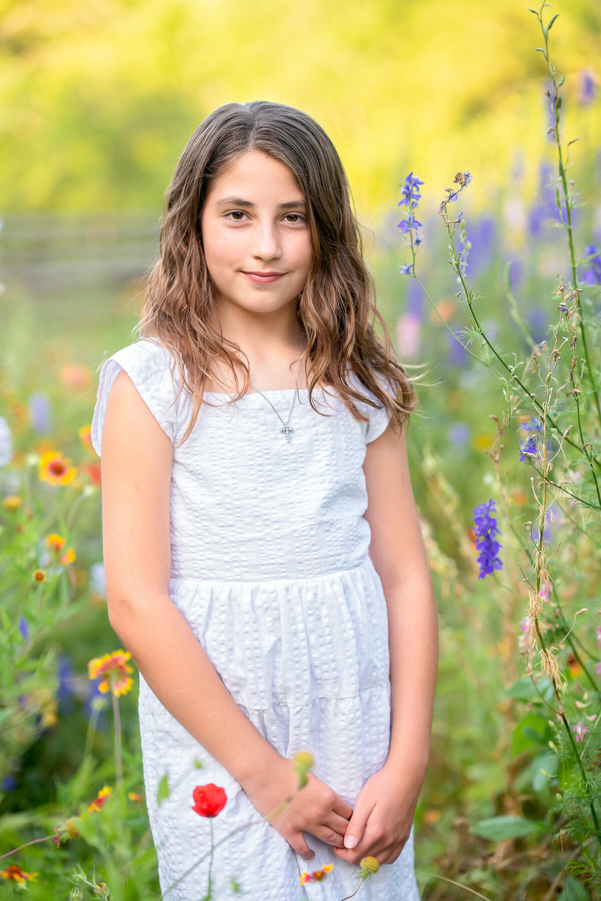 A young girl in a white dress is standing in a field of wildflowers at Turnipseed Farms in Fayetteville, GA.