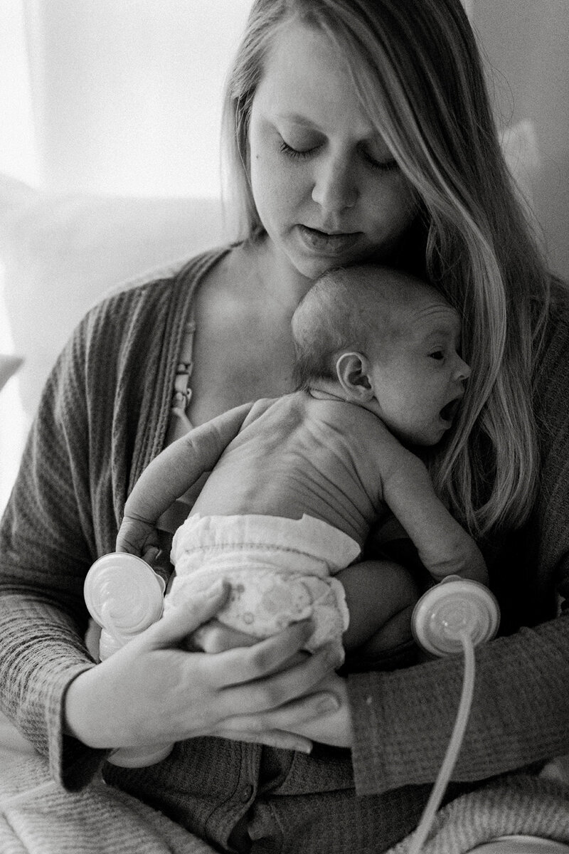 mother multitasks by comforting her newborn baby and pumping