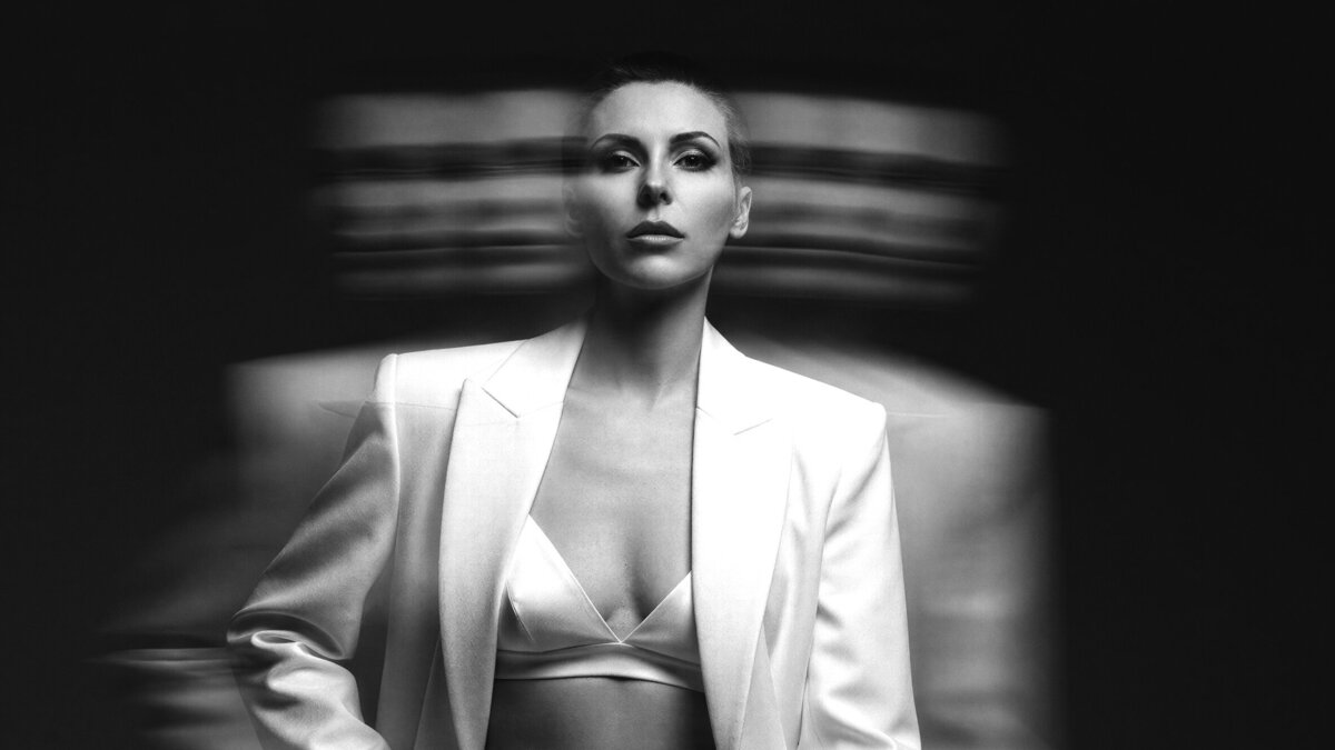 Black and white cinematic portrait of Jasmina Kimova in white suit as apodcast host of Quantum Leap Energy