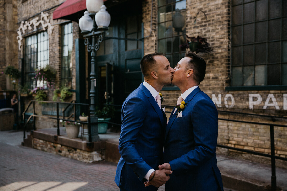 gay husbands kissing in urban wedding