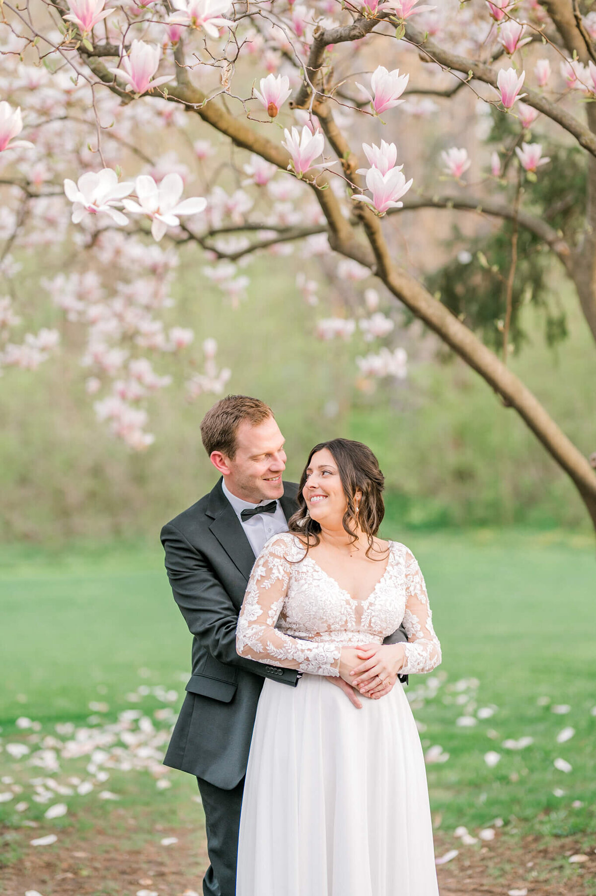 Bride and groom hugging under cherry blossom tree