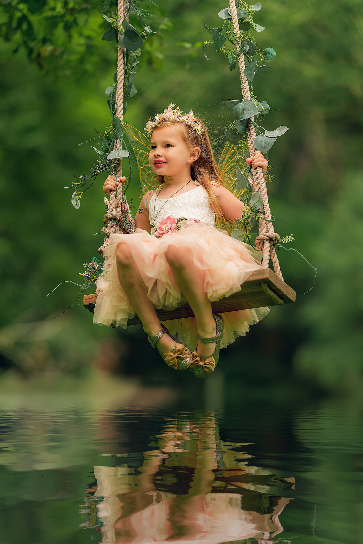 A young girl from Pewaukee, WI sits on a rope swing over a river dressed as a fairy in a tutu.