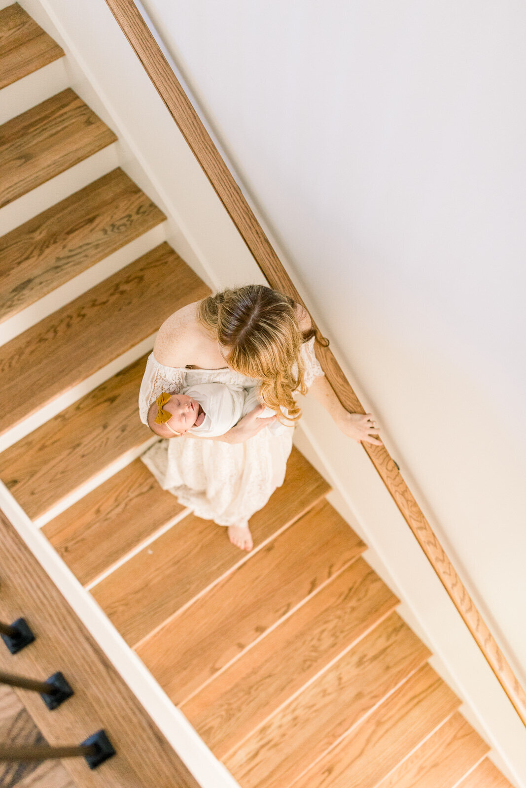 New mother walking with newborn down stairway