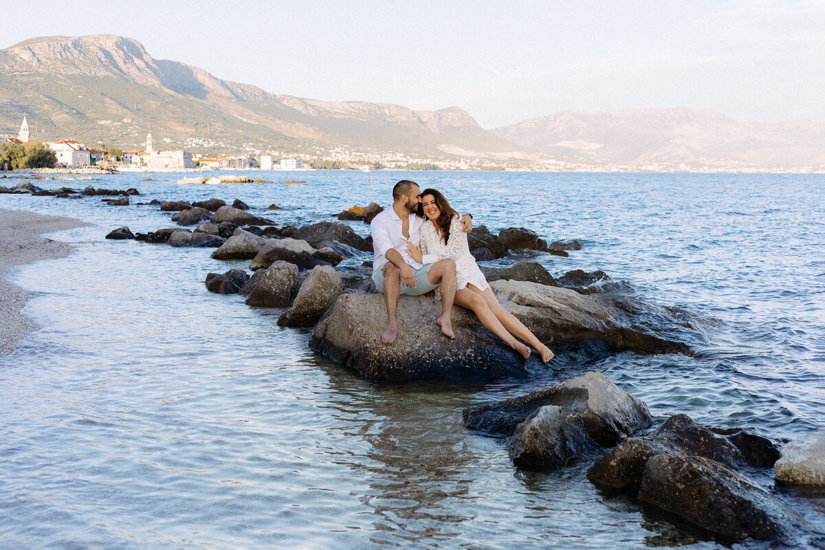 couple sitting on rocks for engagement session in kastela croatia