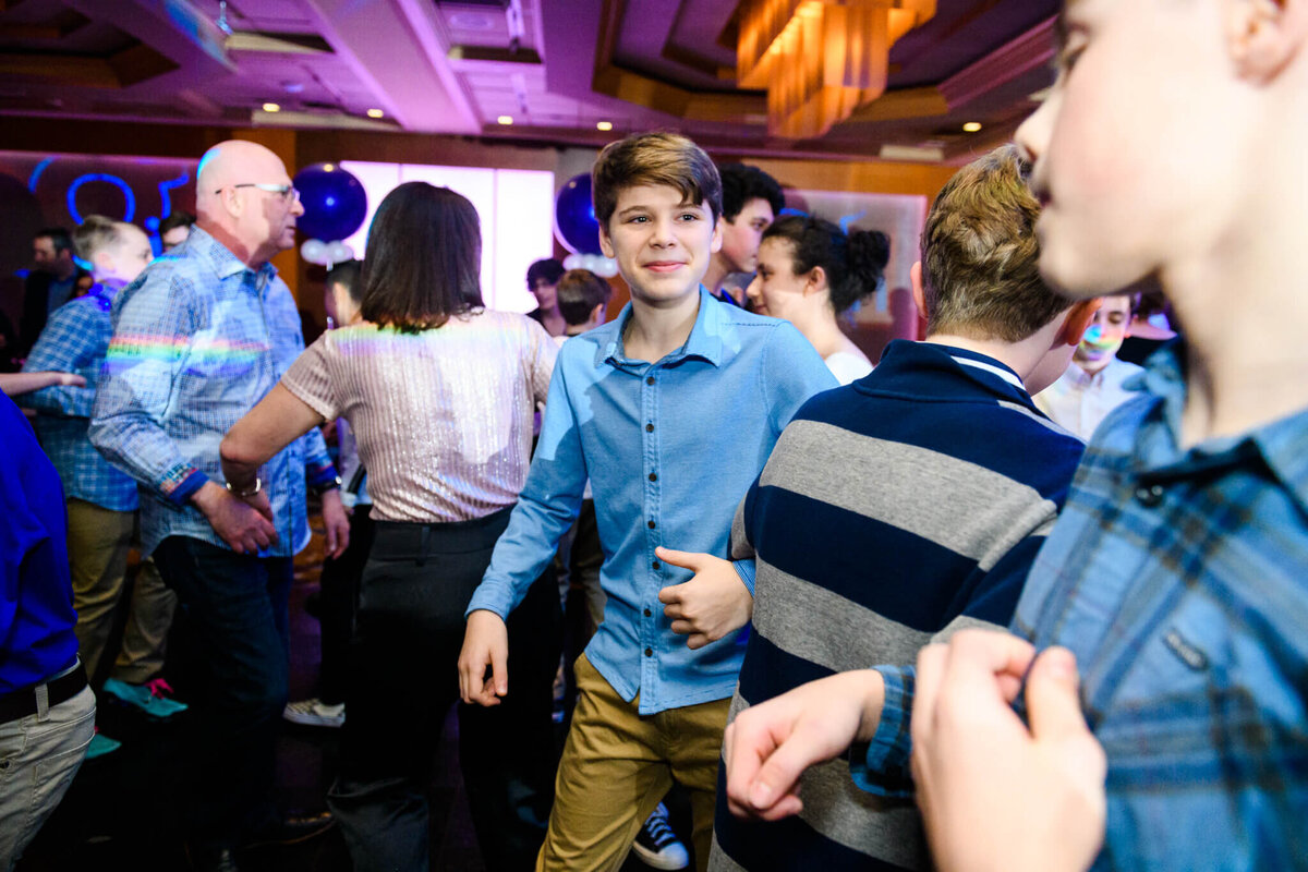 A group of boys and parents dance on a crowded dance floor