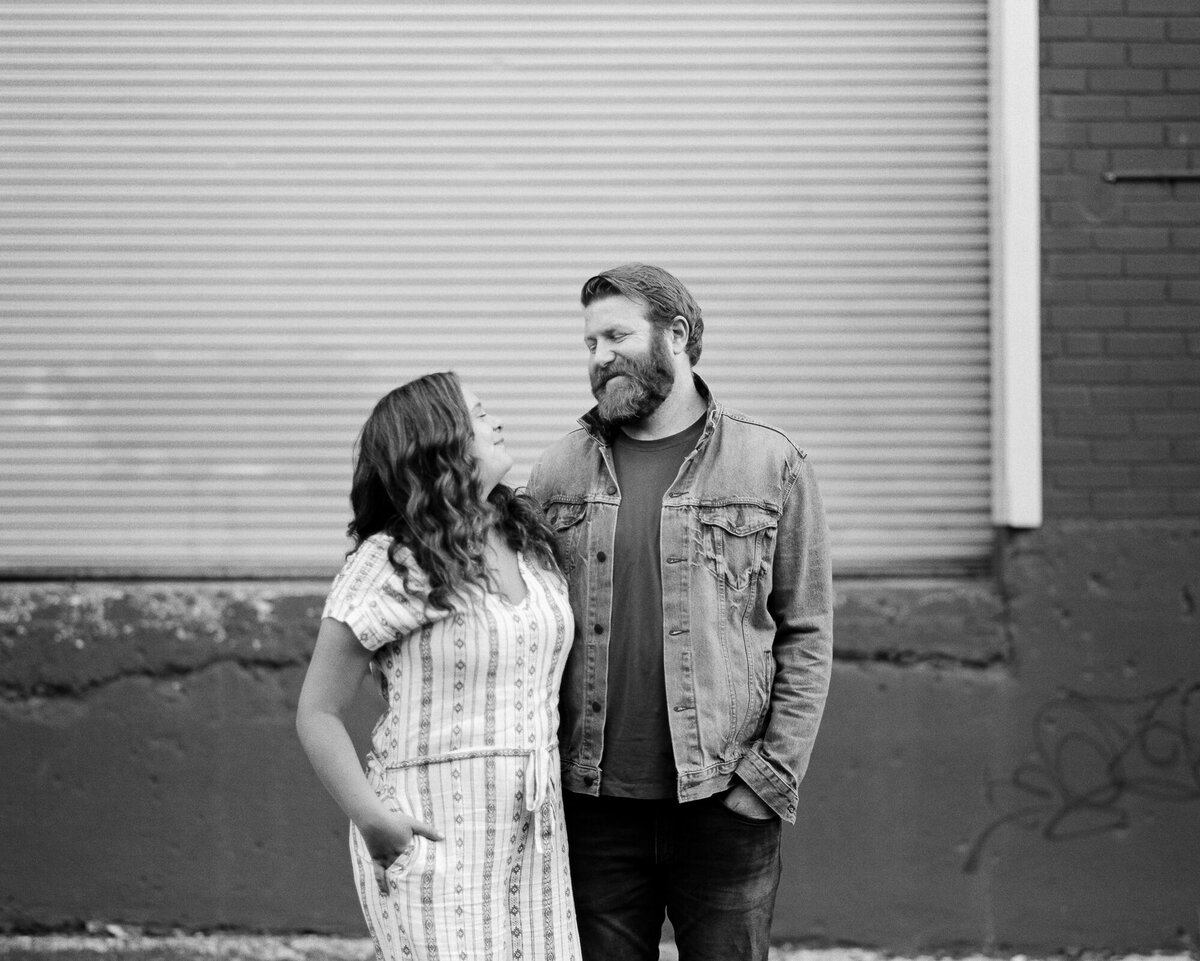 Couple poses in front of garage doors for engagement photos on film