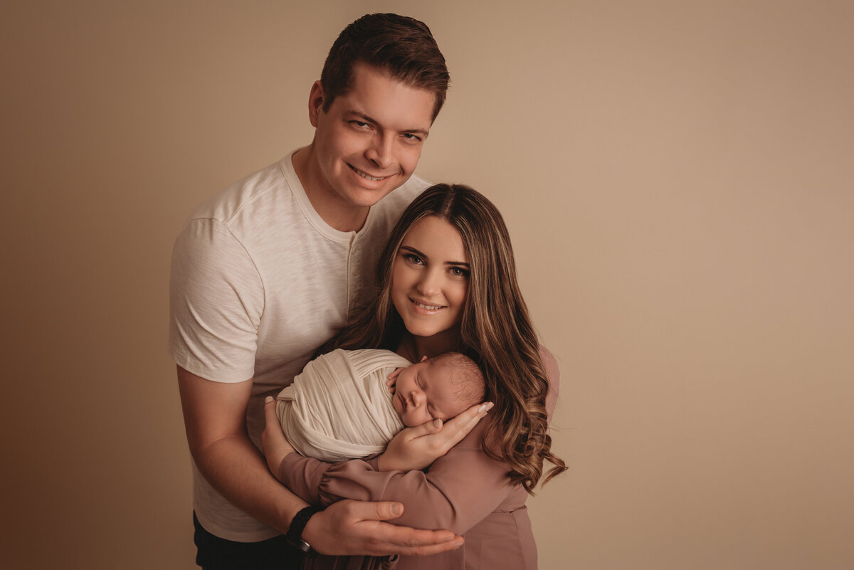 2 week old newborn portrait session with family of three dressed in mauve and creams with mom holding baby at atlanta family newborn photography studio
