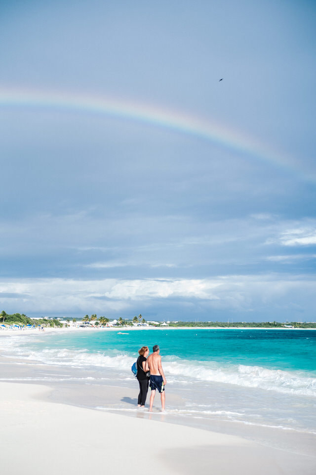 couple standing under a rainbow on the beach in anguilla