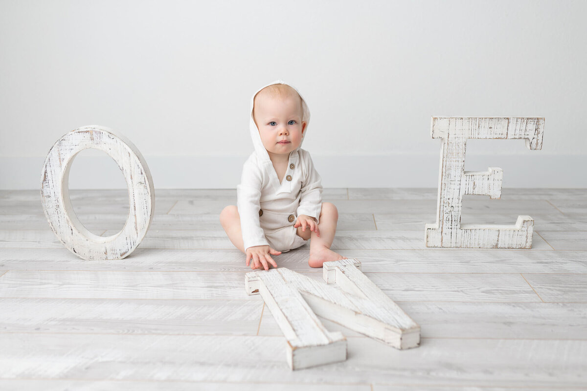 Baby boy with wooden ONE letters as part of his cake smash session