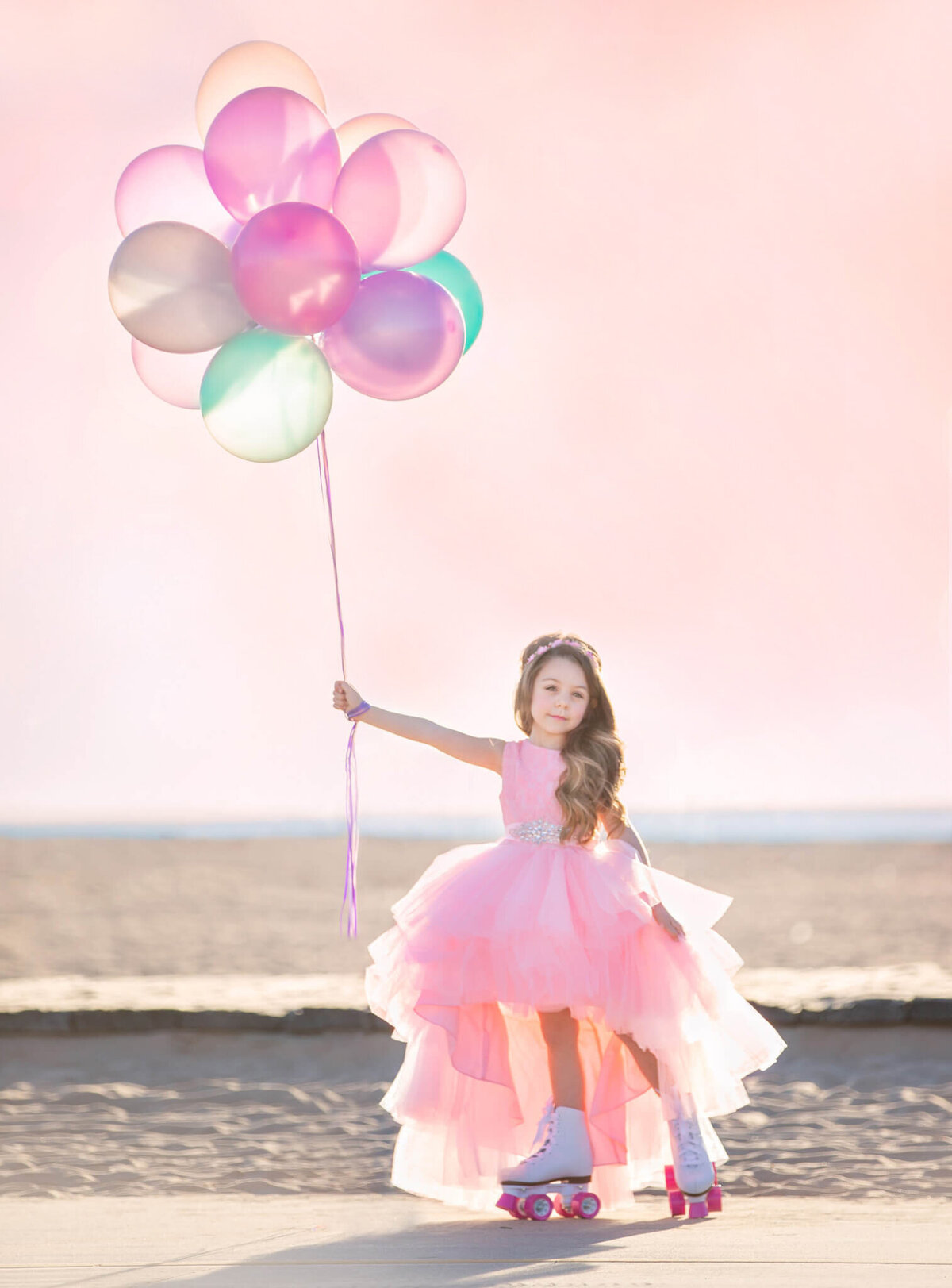 Little girl in roller skates at Santa Monica beach while holding balloons with a pink sky - Los Angeles Children’s Photographer Elsie Rose Photographer