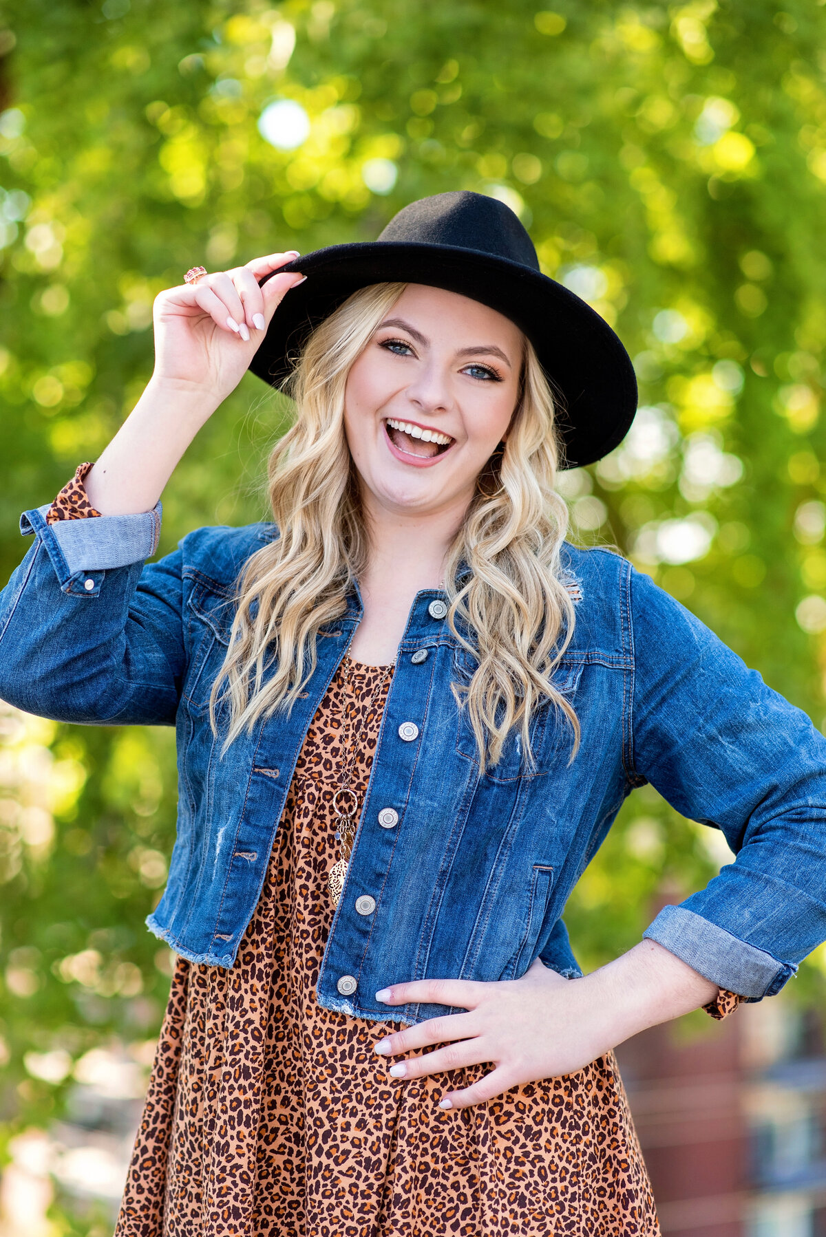 Midlothian high school senior girl wearing animal print dress and denim dress laughs during her portrait session at Libby Hilly Park.