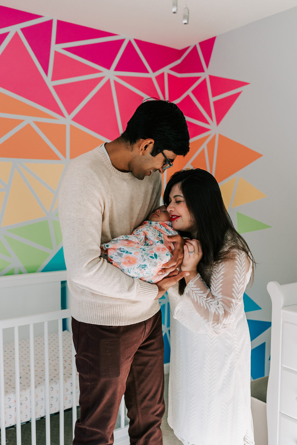 New parents standing in their daughter's nursery with their newborn daughter