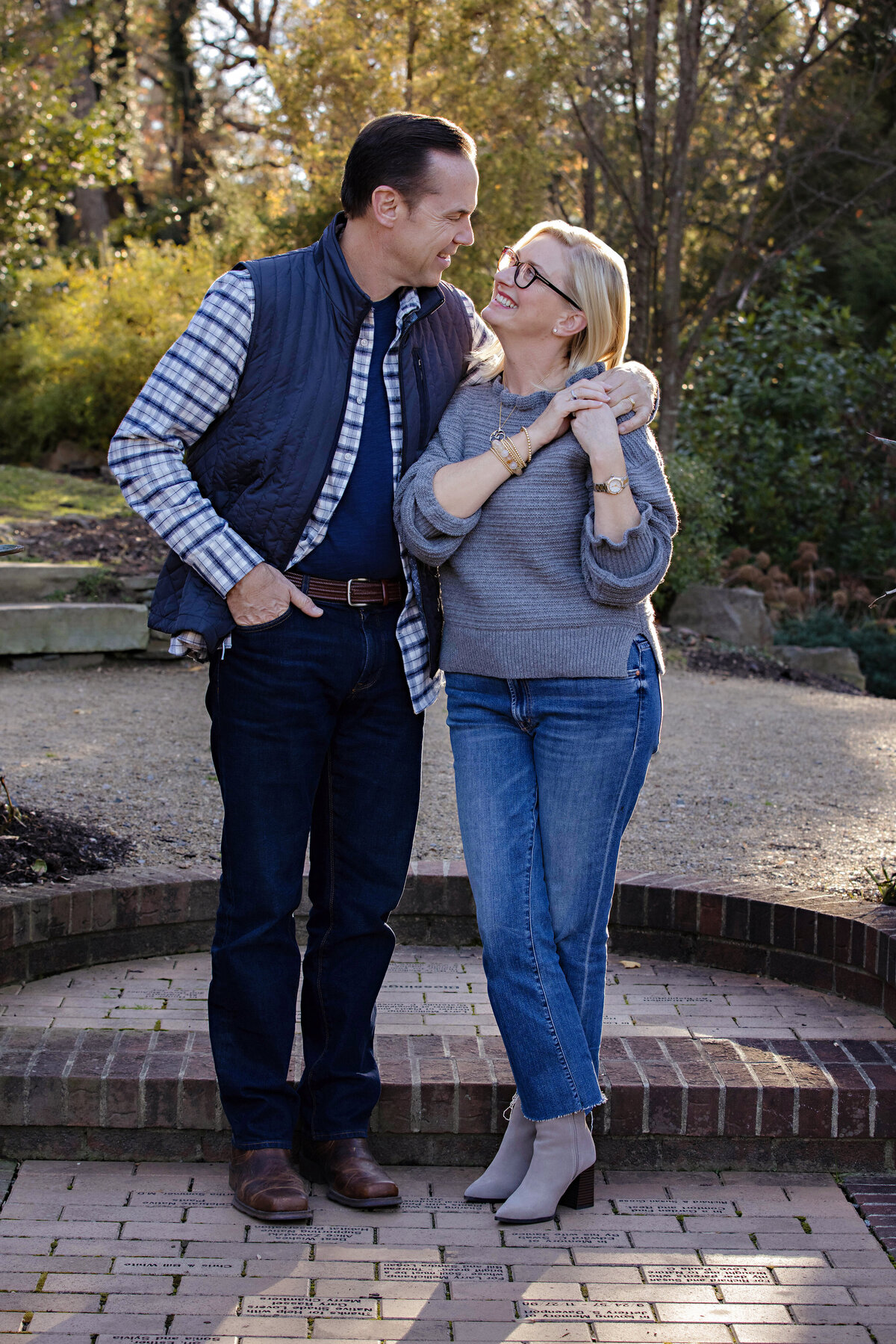 Tender autumn portrait of parents standing close near brick terrace steps at UNCC Botanical Garden Charlotte NC, gazing at each other with affection