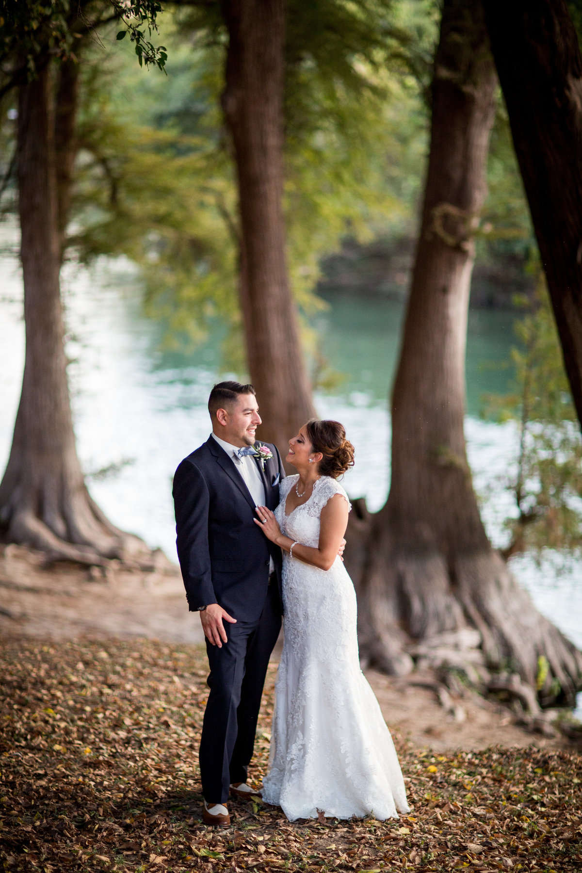 bride and groom standing by river at Milltown Historic District Wedding Venue by San Antonio Wedding photographer