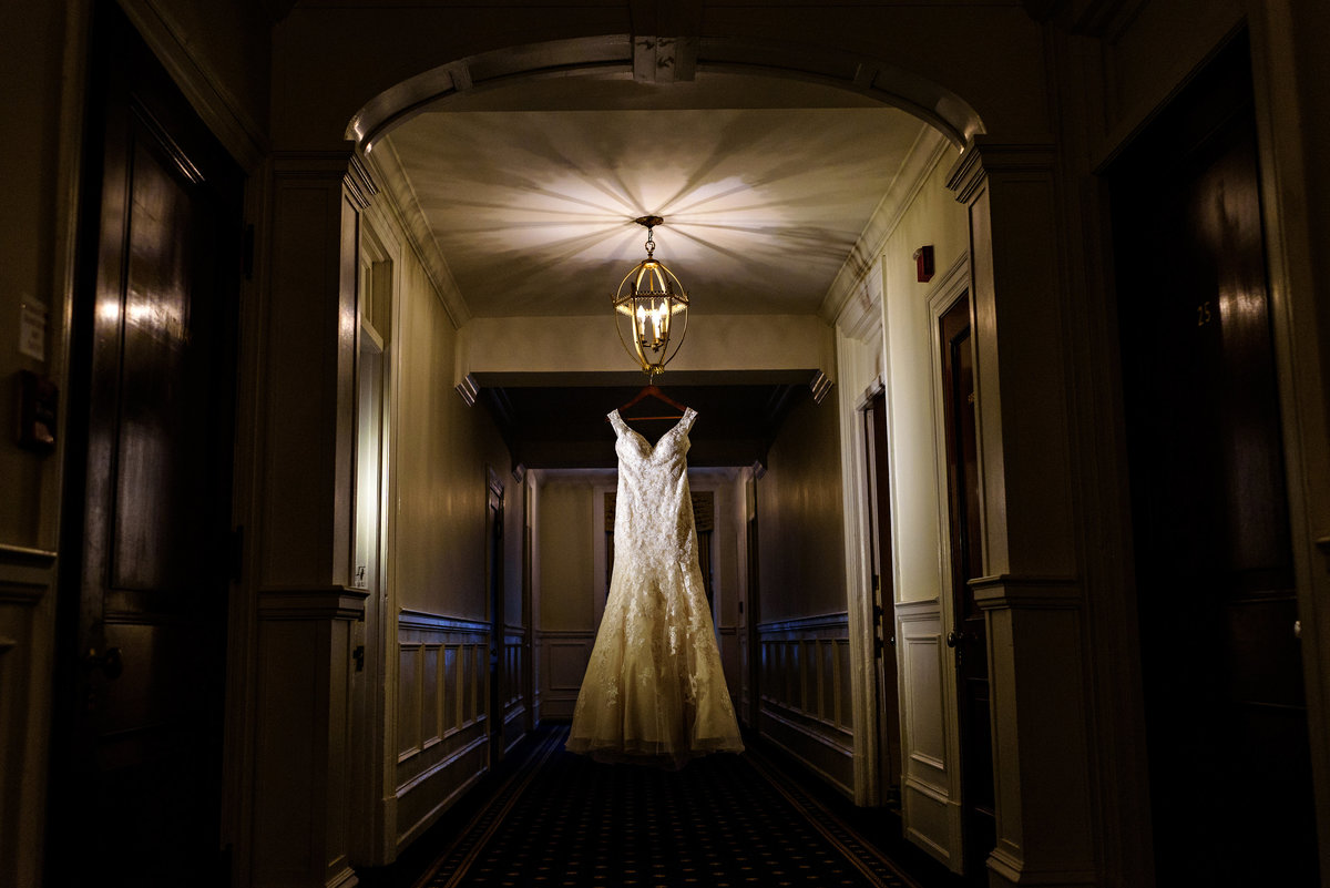 A lace wedding dress hangs in the hallway of the members suites at the racquet club of philadelphia.