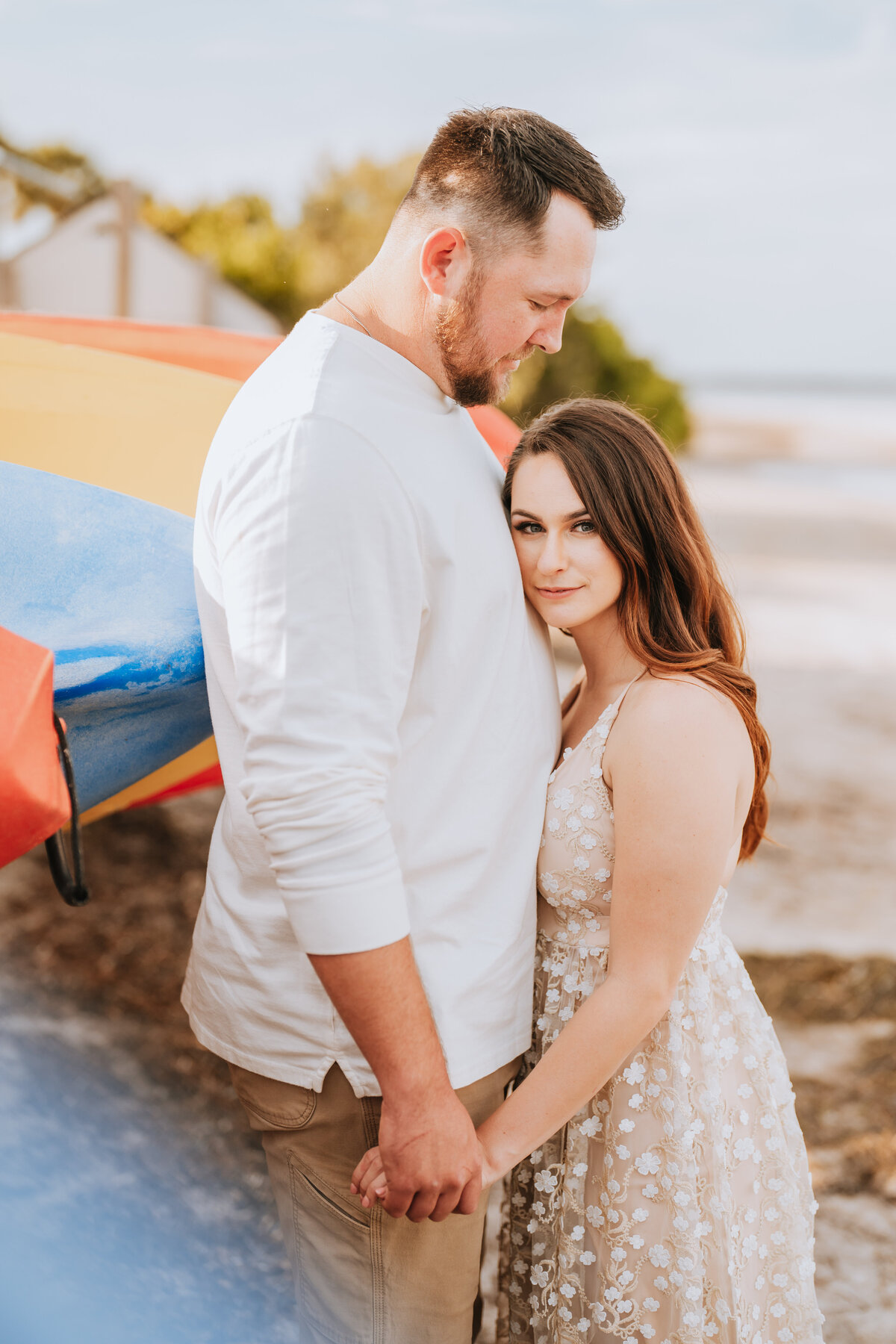 couple snuggling on beach during engagement session