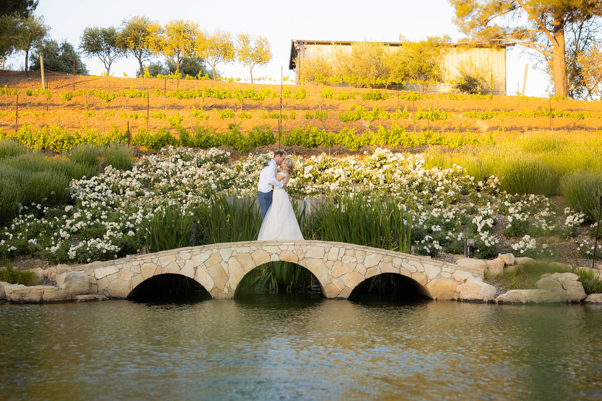 Bride and groom kiss on top of a small bridge with water in the foreground. Photo by Philippe Studio Pro, sacramento wedding photographer.