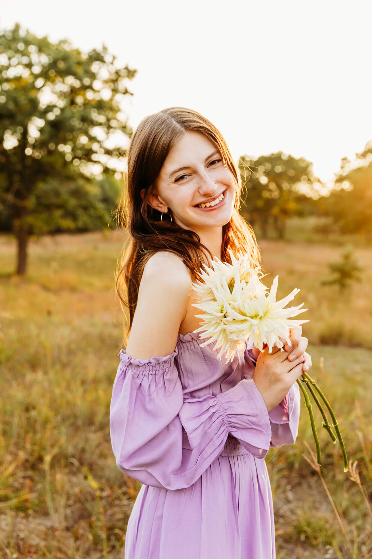 gorgeous teen girl holding white flowers while wearing purple dress captured by Green Bay senior photographer Ashley Kalbus