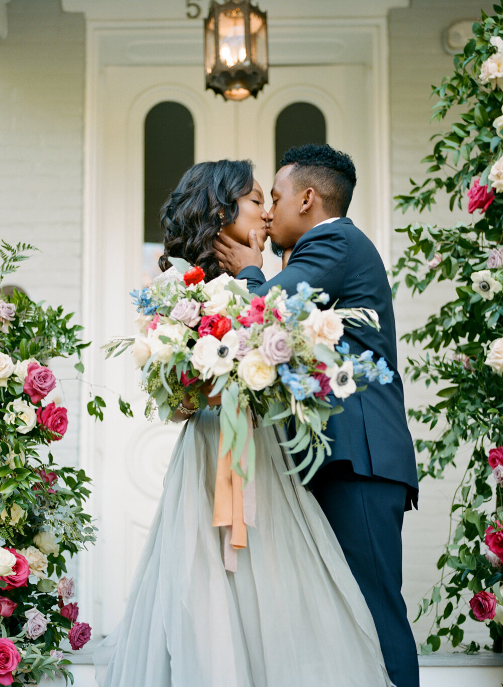 bride and groom kissing with lavish wedding bouquet