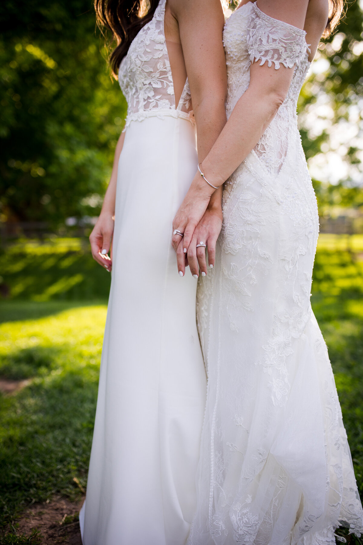 A close up detail shot of two brides' hands intertwined.