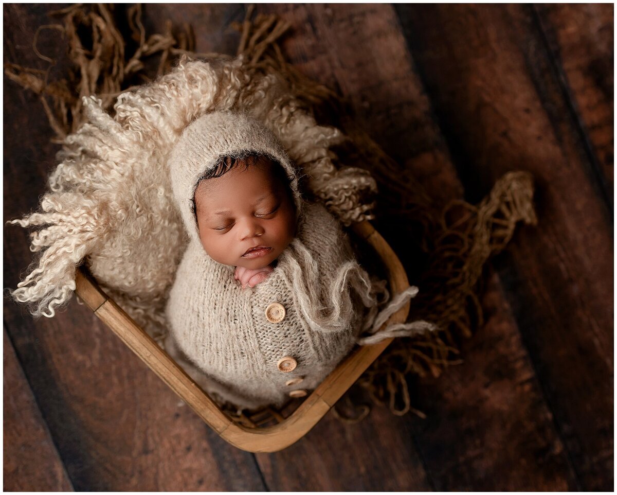 A newborn baby swaddled in a  knit wrap in a basket.