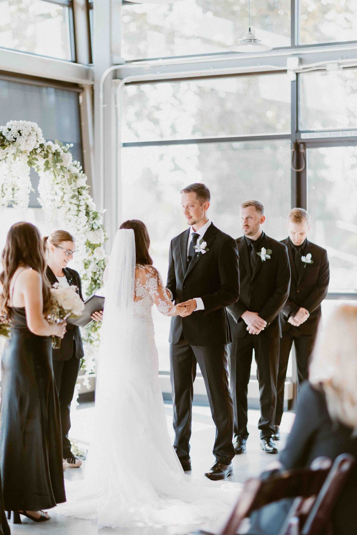 A view of a bride and groom holding hands during their indoor ceremony