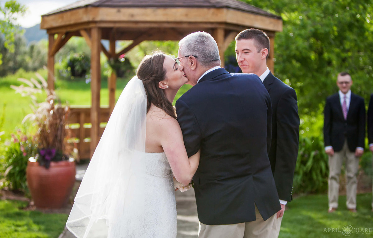 Sweet Colorado wedding photo of bride kissing her dad at Denver Botanic Gardens Chatfield Farms
