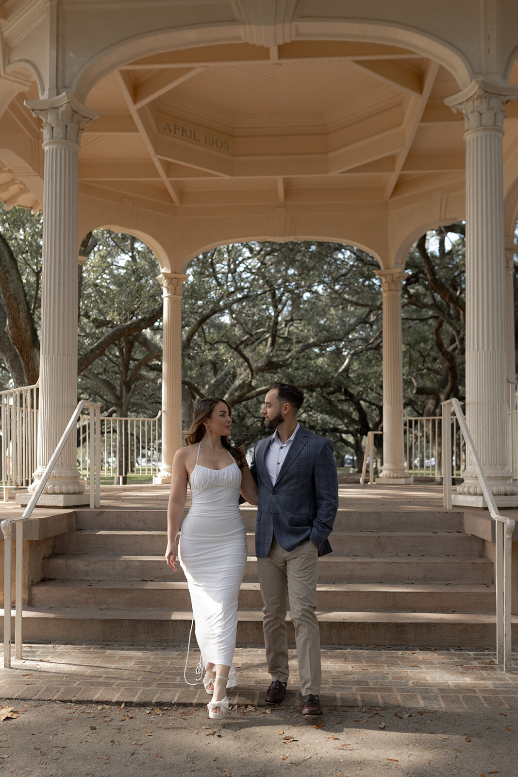 Couple walking towards camera with White Point Garden gazebo in background providing backdrop for Charleston Engagement Photo locations