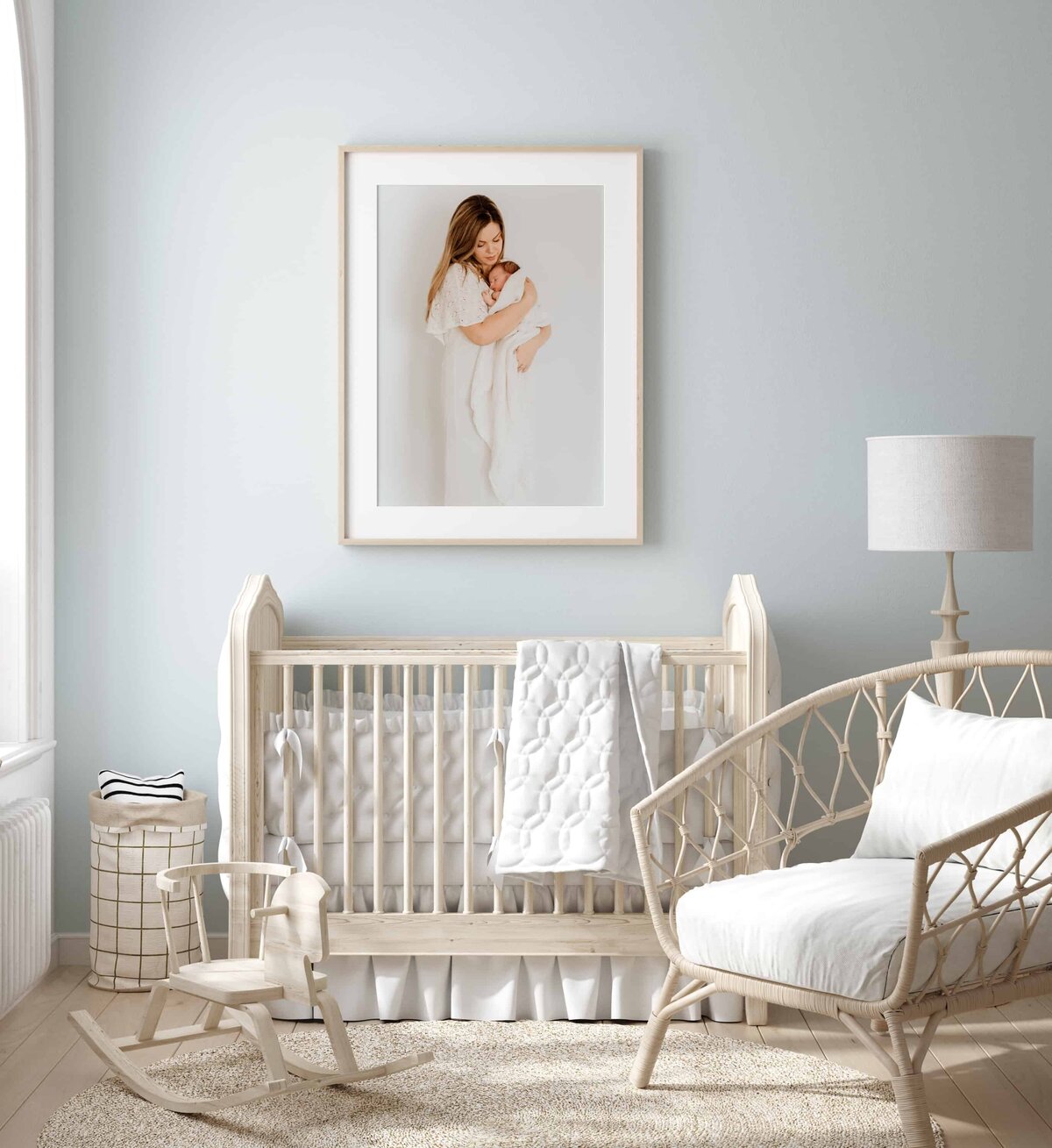 Interiør av et babyrom med et stort rammet bilde fra nyfødtfotografering i Oslo på veggen over babyseng.