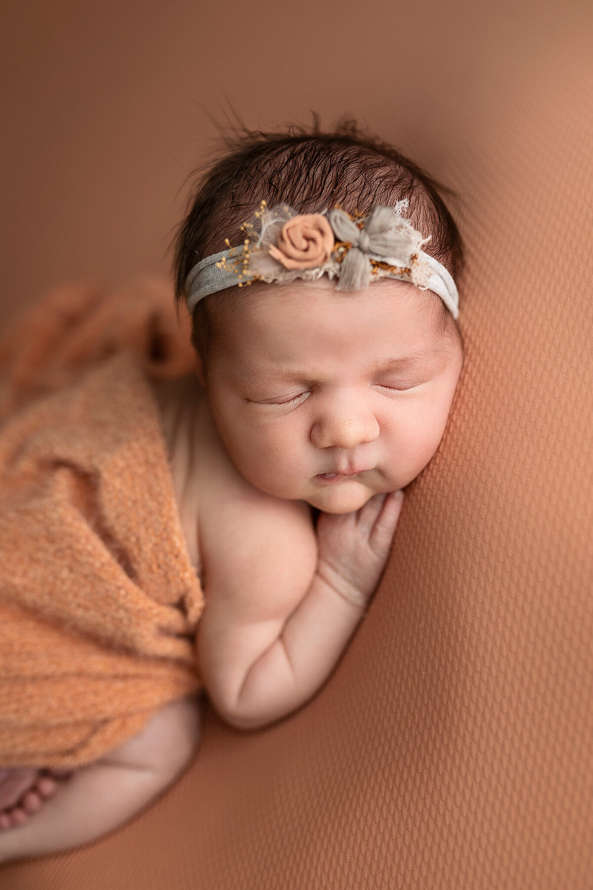 Posed little girl on burnt orange during her newborn session.