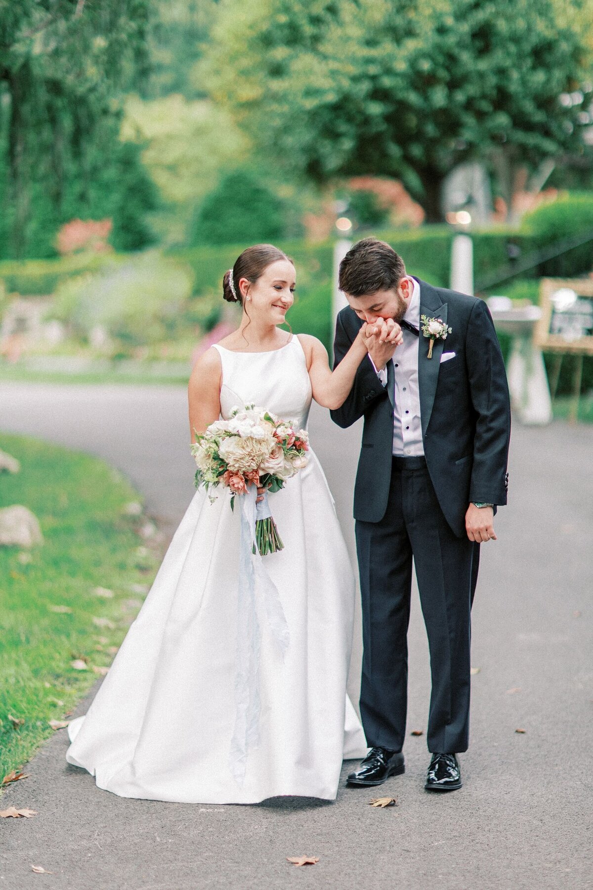 Groom kissing bride's hand beautiful green pathway