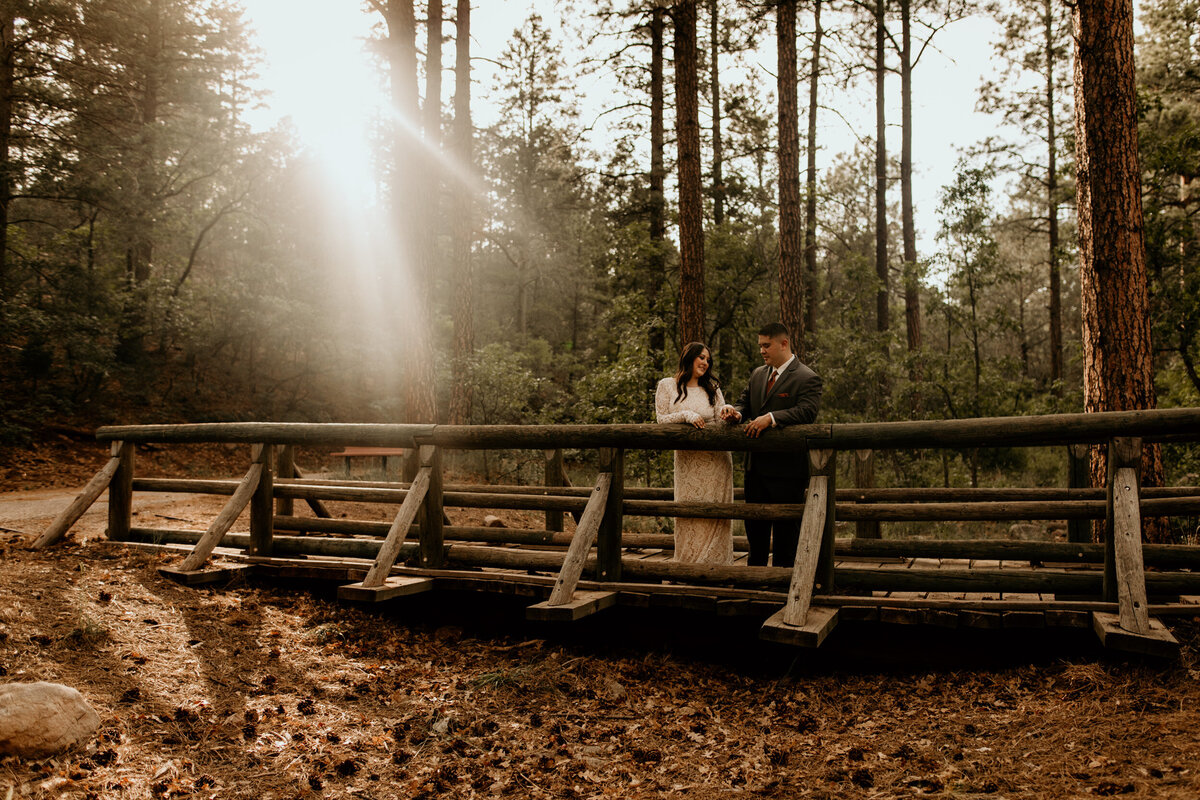 bride and groom standing on a bridge together in the forest in New Mexico