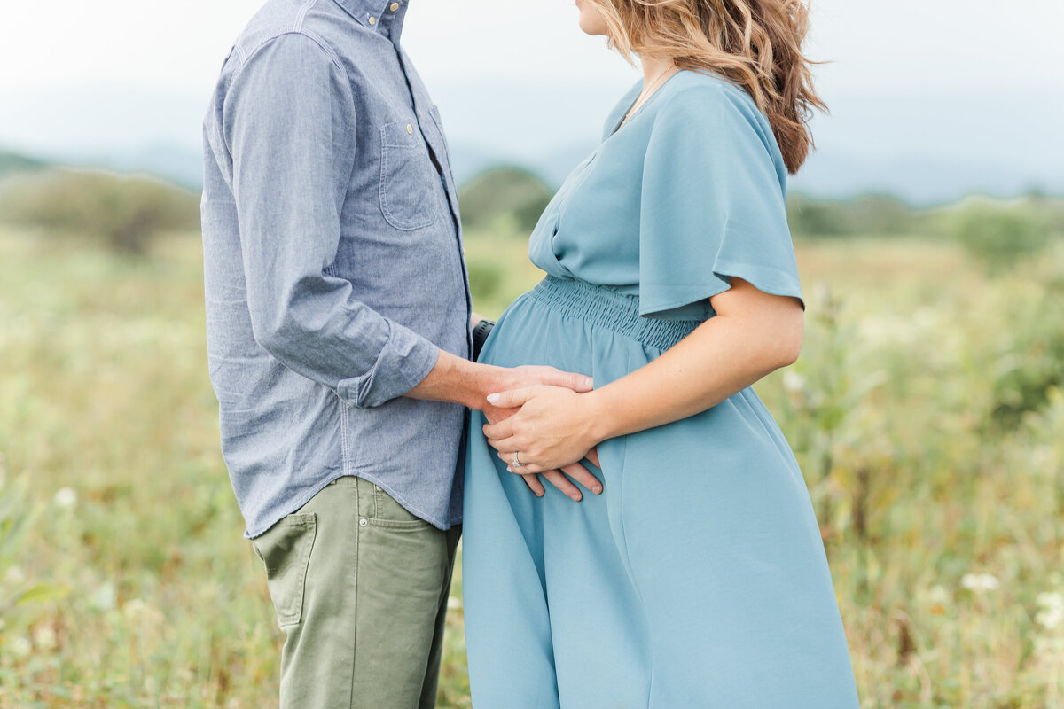 A closeup Northern Virginia Maternity Photographer Northern Virginia Maternity Photographer photo of a pregnant couple holding the mother's belly in a field