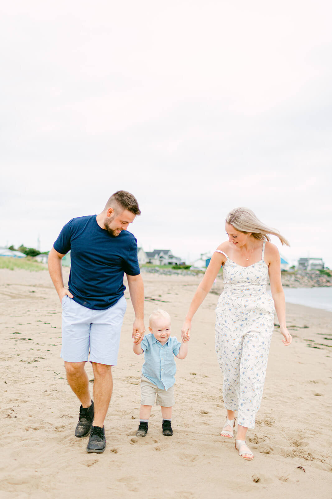 two-parents-walking-on-beach-with-kid