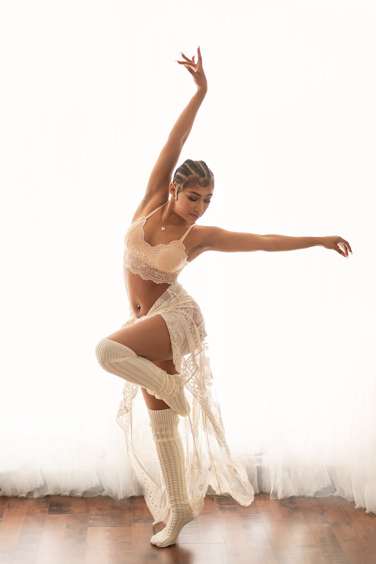 A dancer poses in all white lingerie for a boudoir session in our Waukesha, WI photo studio.
